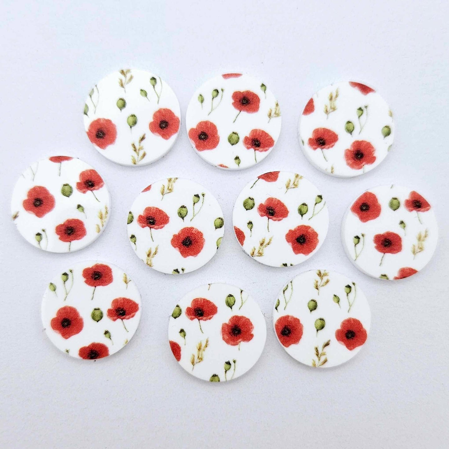Multiple 20mm Poppy UV printed stud earring blanks featuring detailed poppy blooms and green foliage on white acrylic laying flat.