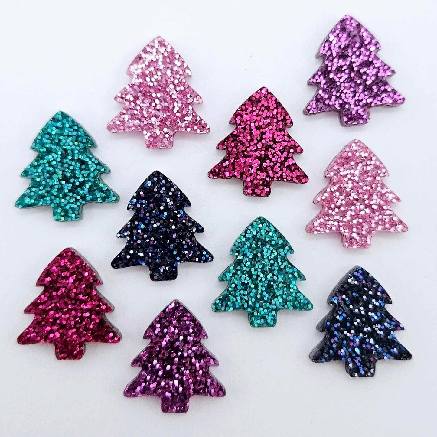 Five colours of 16mm glitter Christmas tree stud earring blanks in hot pink, teal, purple, pink and holographic blue acrylic laying flat.