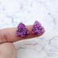 One pair of 16mm purple glitter Christmas tree stud earring blanks shown on a finger for size reference.