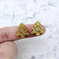 One pair of gold glitter acrylic 16mm Christmas tree stud blanks, shown on a finger for size reference.