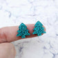 One pair of 16mm teal glitter Christmas tree stud earring blanks shown on a finger for size reference.