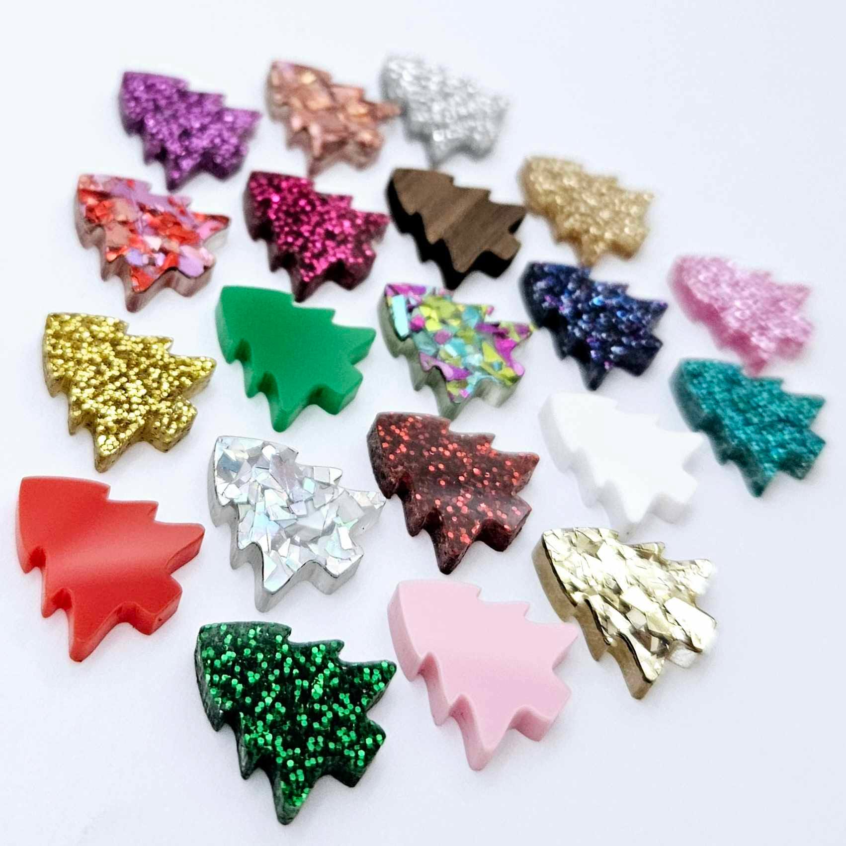 One of each of the 20 acrylic colours of 16mm Christmas tree stud earring blanks laying flat.