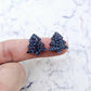 One pair of 16mm holographic blue glitter Christmas tree stud earring blanks shown on a finger for size reference.