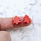 One pair of 12mm solid red acrylic Christmas tree stud earring blanks shown on a finger for size reference.