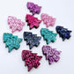 Five colours of 16mm glitter Christmas tree stud earring blanks in hot pink, teal, purple, pink and holographic blue acrylic laying flat.