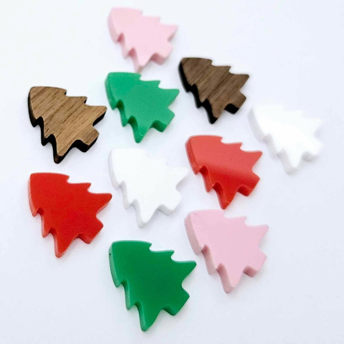 Solid acrylic and walnut veneer 16mm Christmas tree stud earring blanks in green, red, white, pastel pink and walnut laying flat.