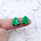 One pair of 12mm solid green acrylic Christmas tree stud earring blanks shown on a finger for size reference.