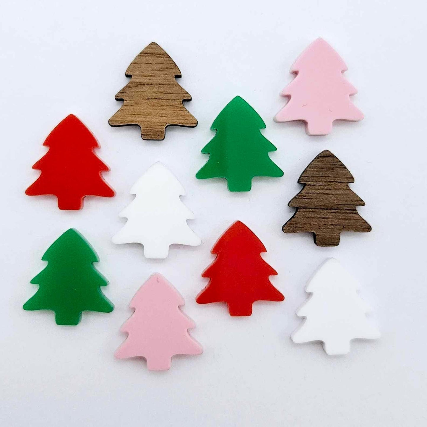 Five colours of 16mm Christmas tree stud earring blanks in green, red, white and pastel pink solid acrylic and walnut veneer laying flat.