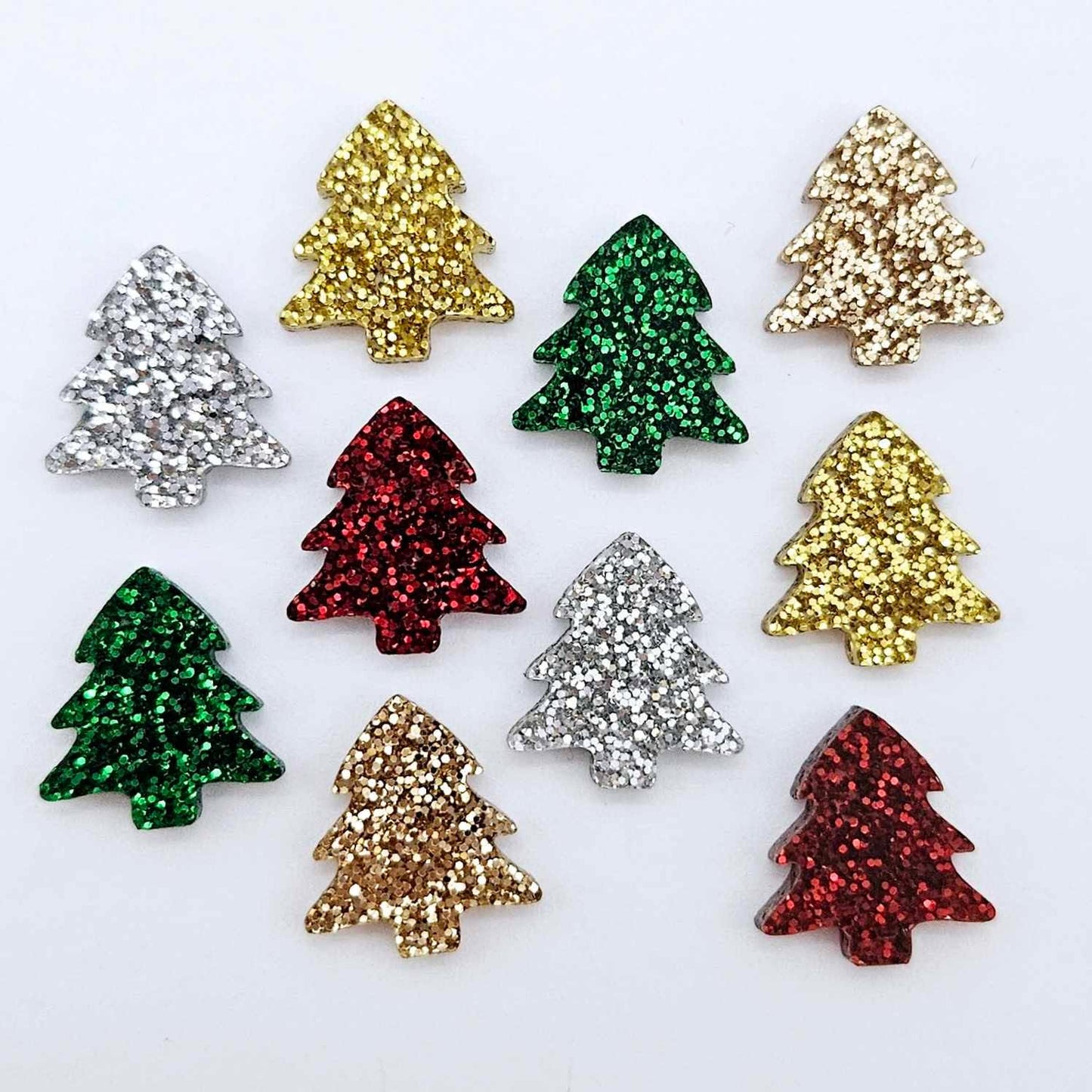 One pair of 16mm Christmas tree stud earring blanks in green glitter, red glitter, gold glitter, silver glitter and rose gold glitter acrylic laying flat.