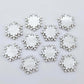 Five pairs of 16mm white marble acrylic snowflake stud earring blanks laying flat.