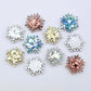 Five colours of 16mm snowflake stud earring blanks in holographic silver, aqua, chunky gold, holographic rose gold glitter and white marble acrylic laying flat.
