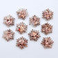 Five pairs of 16mm chunky rose gold glitter acrylic snowflake stud earring blanks laying flat.