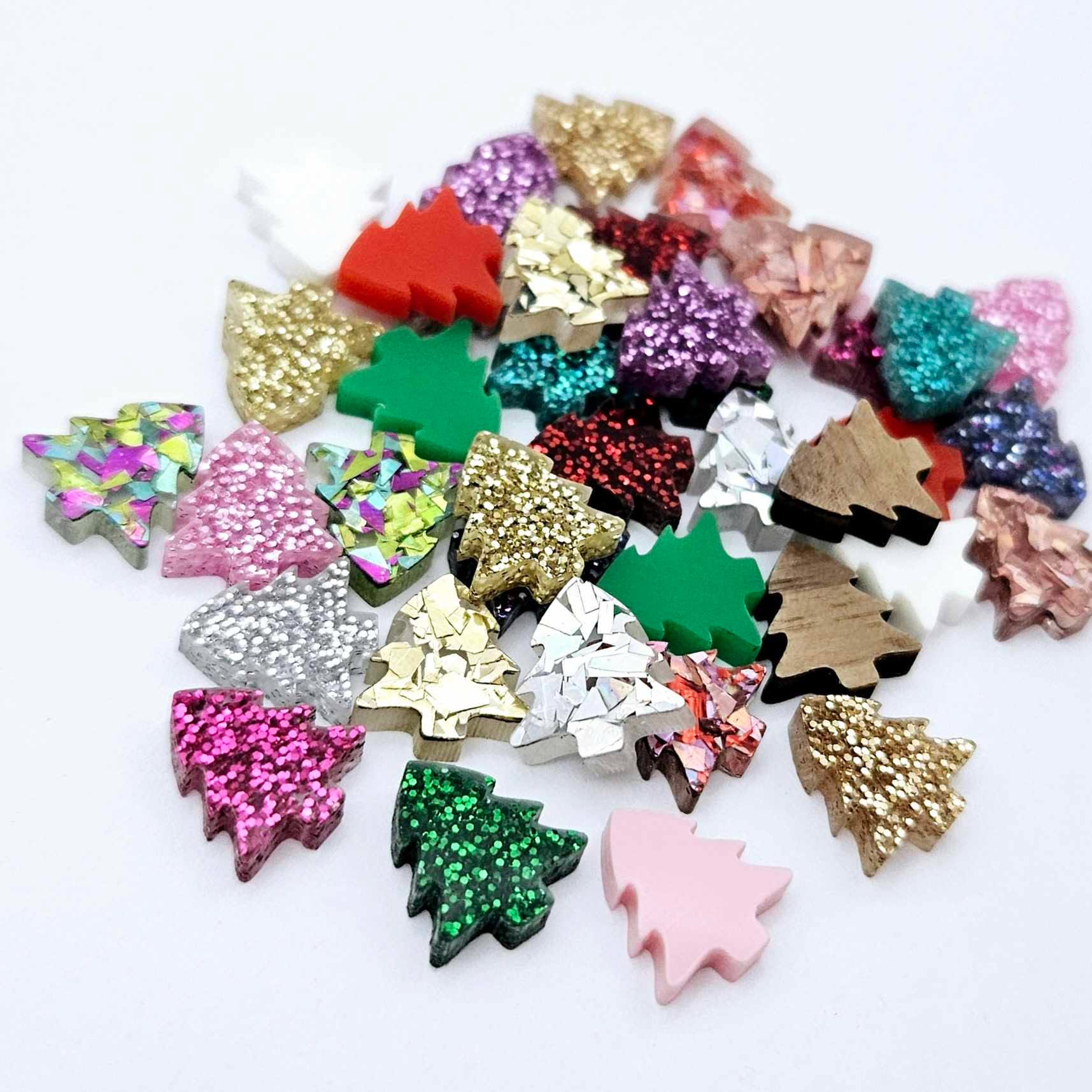 All 20 colours and finishes of 12mm mini Christmas tree stud earring blanks laying together, including glitter, solid acrylic and walnut veneer.