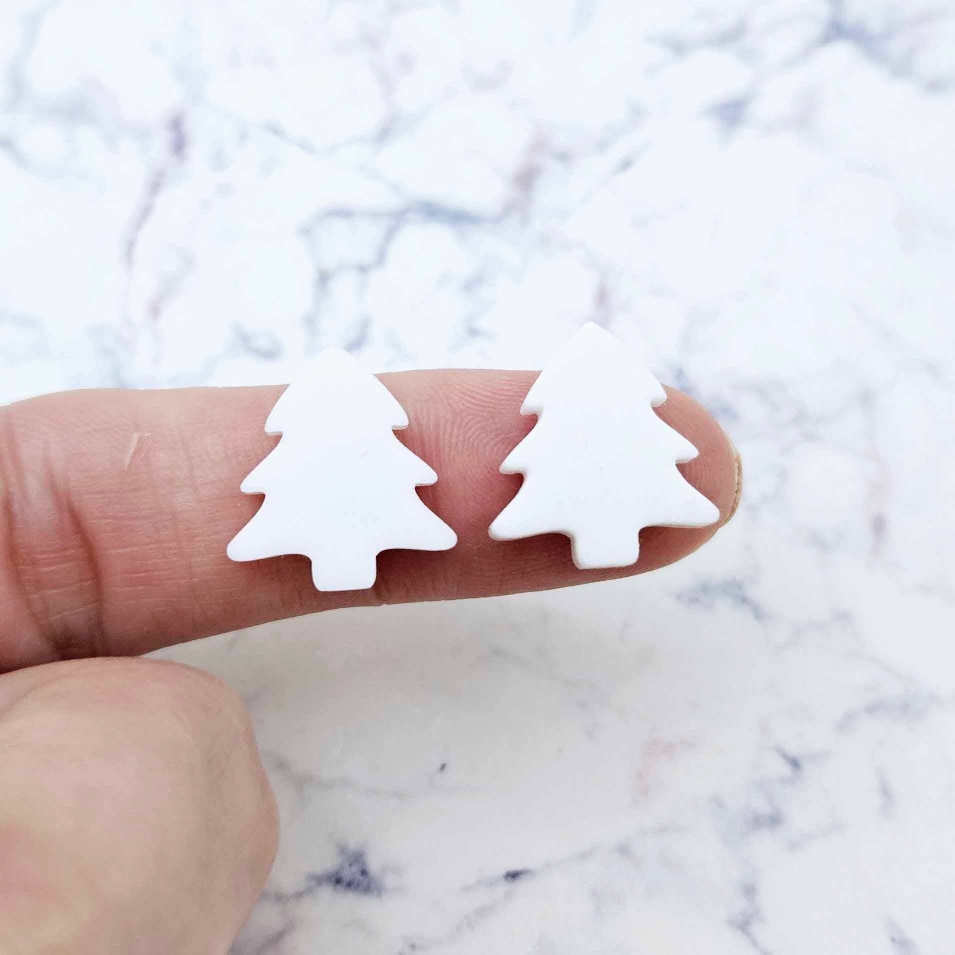 One pair of 16mm White acrylic Christmas tree stud earring blanks shown on a finger for size reference.