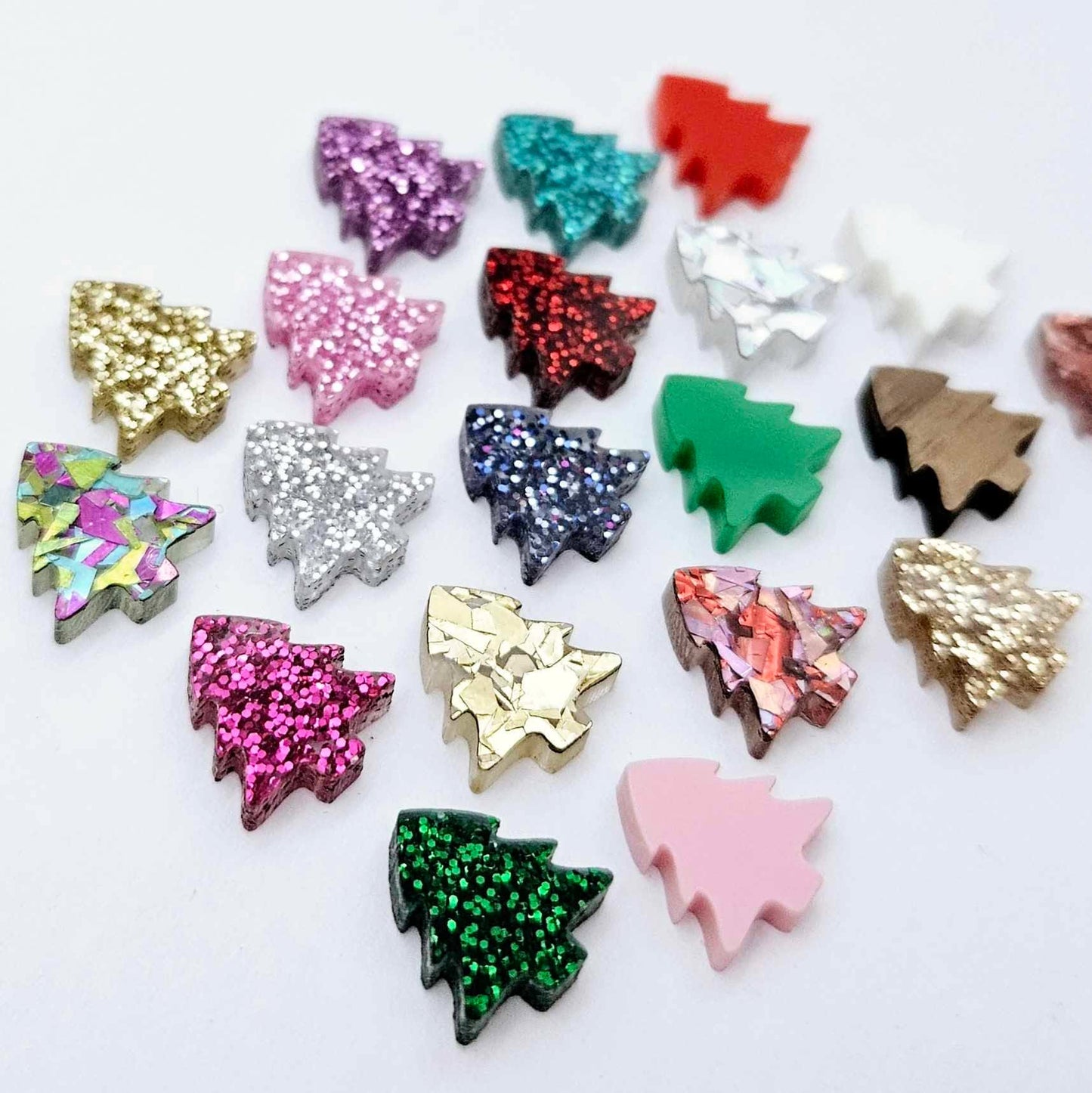 All 20 colours and finishes of 12mm mini Christmas tree stud earring blanks laying together, including glitter, solid acrylic and walnut veneer.
