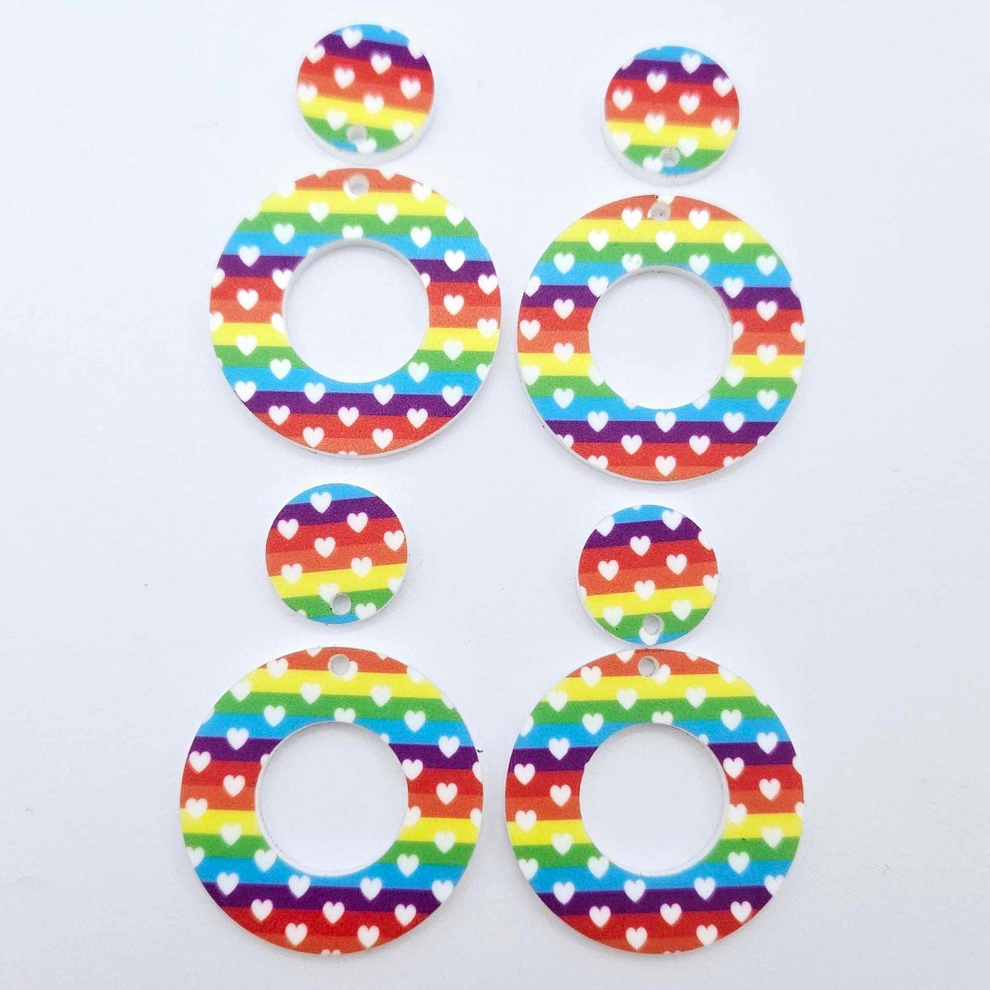 Two pairs of 33mm Rainbow Love UV printed acrylic mini hoop dangle earring blanks with matching toppers laying flat.
