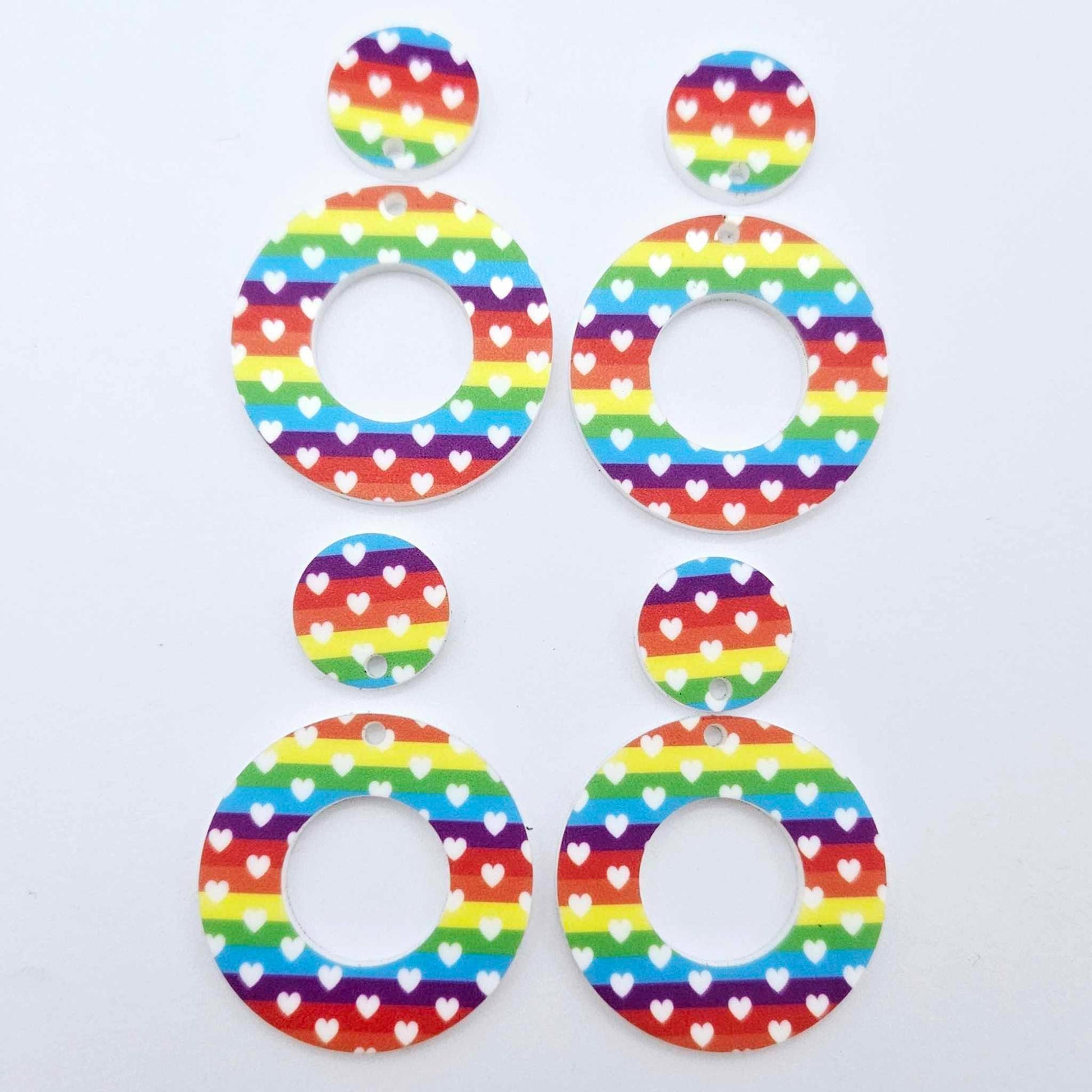 Two pairs of 33mm Rainbow Love UV printed acrylic mini hoop dangle earring blanks with matching toppers laying flat.