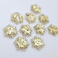 Five pairs of 16mm chunky gold glitter acrylic snowflake stud earring blanks laying flat.
