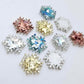 Five colours of 16mm snowflake stud earring blanks in holographic silver, aqua, chunky gold, holographic rose gold glitter and white marble acrylic laying flat.