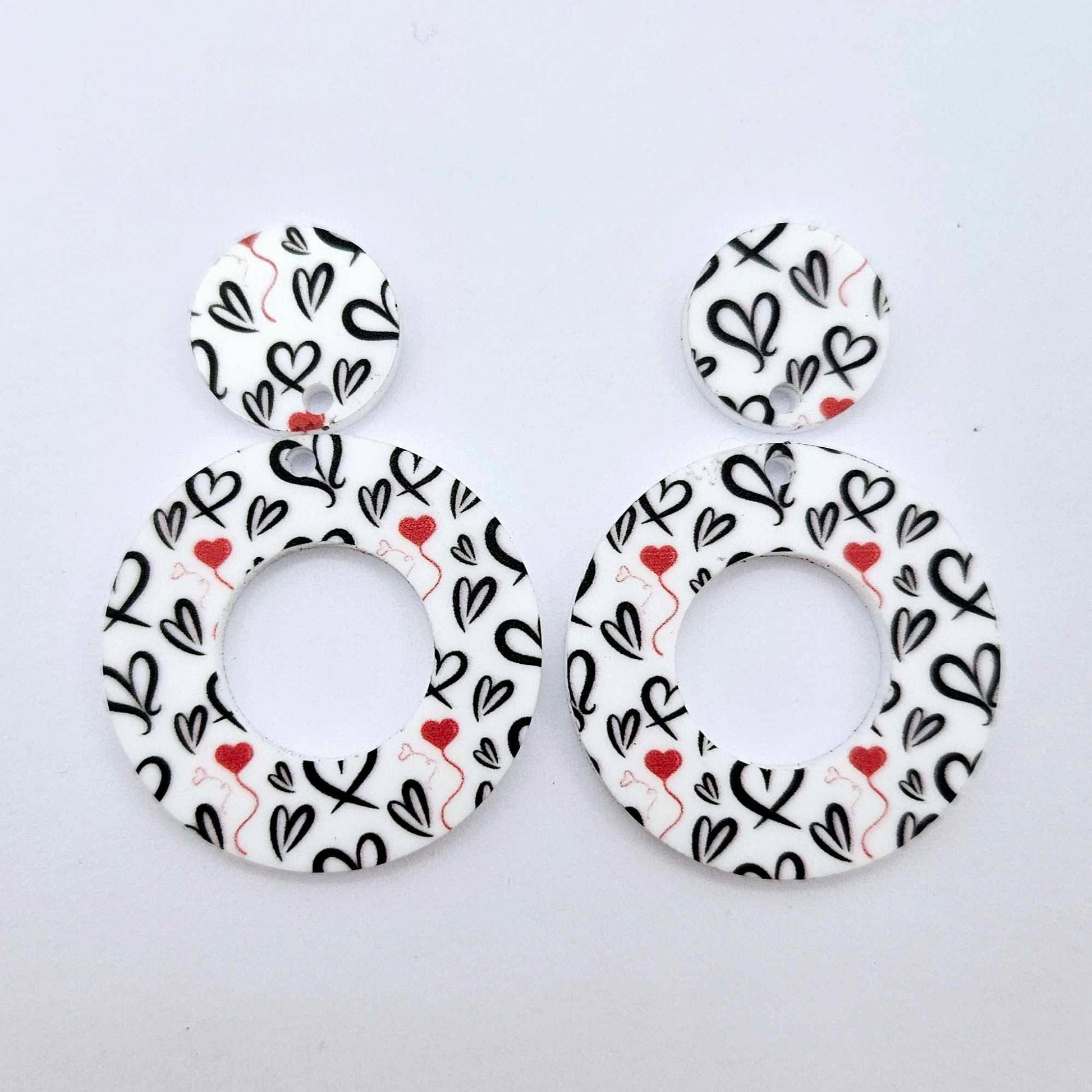 One pair of 33mm Black & Red Hearts UV printed acrylic mini hoop dangle earring blanks with matching toppers laying flat.