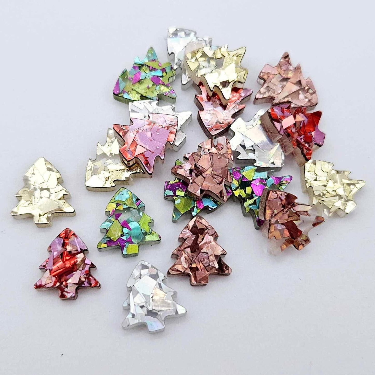 20 pieces of 12mm chunky glitter acrylic Christmas tree stud earring blanks in five sparkling colours piled together.