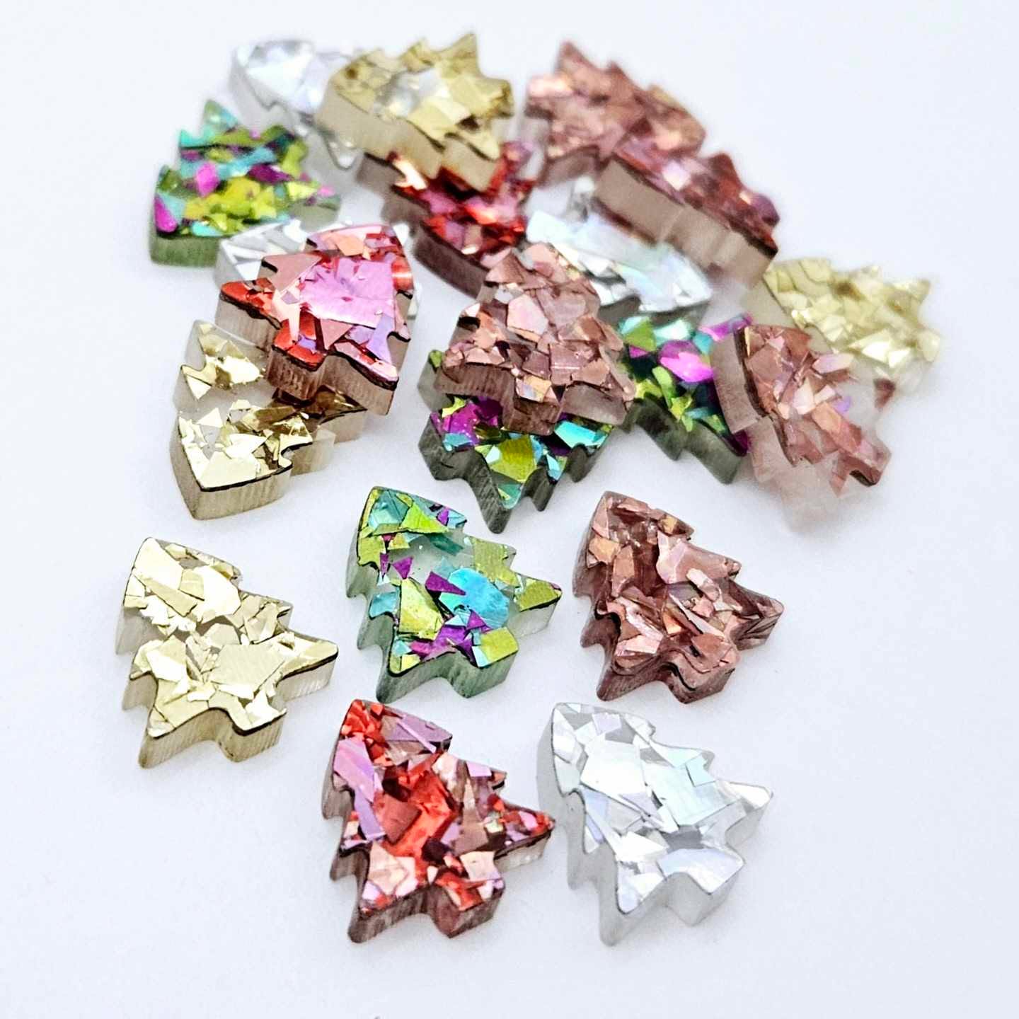 20 pieces of 12mm chunky glitter acrylic Christmas tree stud earring blanks in five sparkling colours piled together.