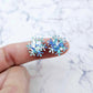 One pair of 16mm chunky aqua glitter acrylic snowflake stud earring blanks shown on a finger for size reference.