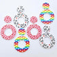 Three pairs of 33mm Love is Love UV printed acrylic mini hoop dangle earring blanks with matching toppers in Rainbow Love, Pink & Red Hearts and Red & Black Hearts designs laying flat.