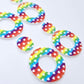 Two pairs of 33mm Rainbow Love UV printed acrylic mini hoop dangle earring blanks with matching toppers laying flat.