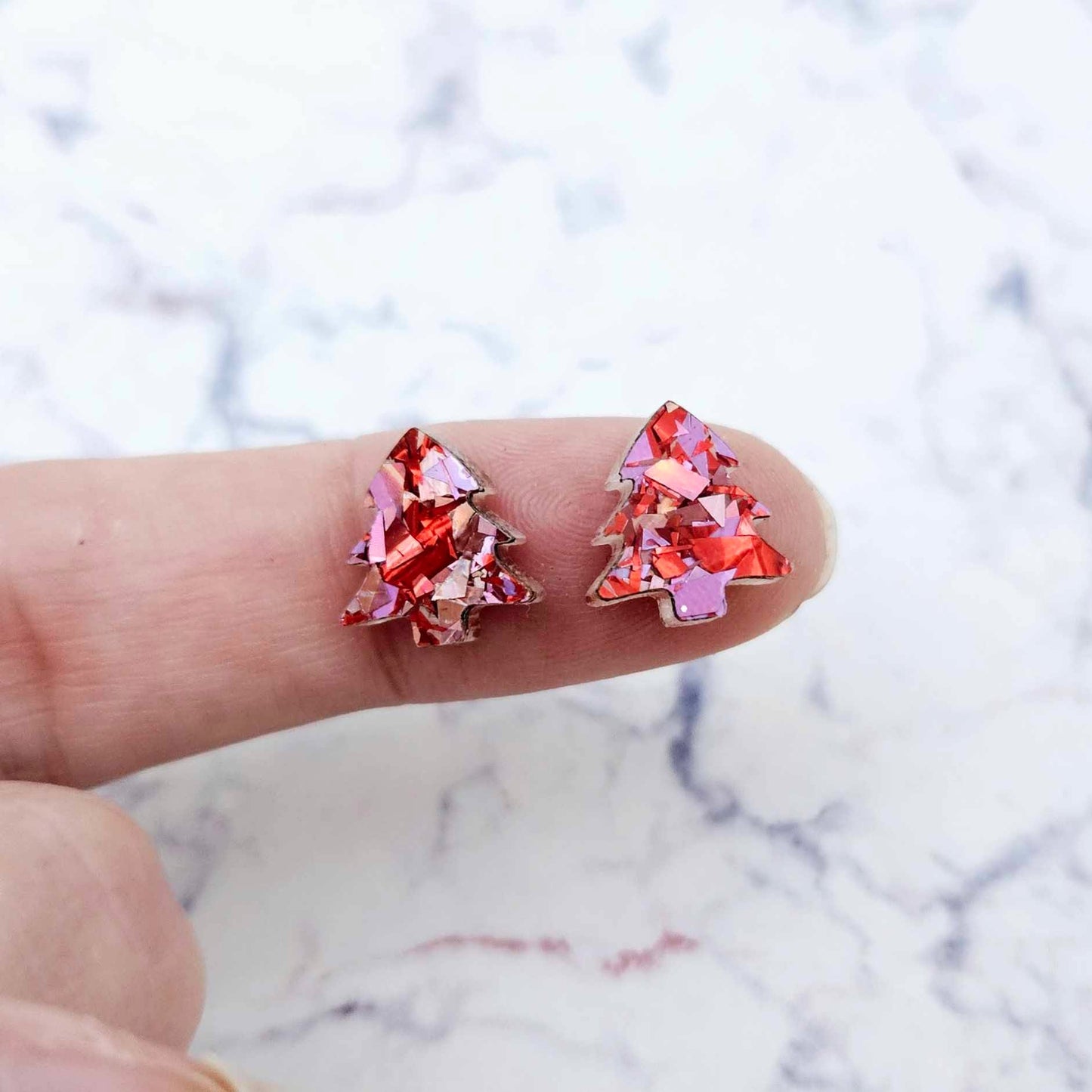 One pair of 12mm chunky love glitter acrylic Christmas tree stud earring blanks shown on a finger for size reference.