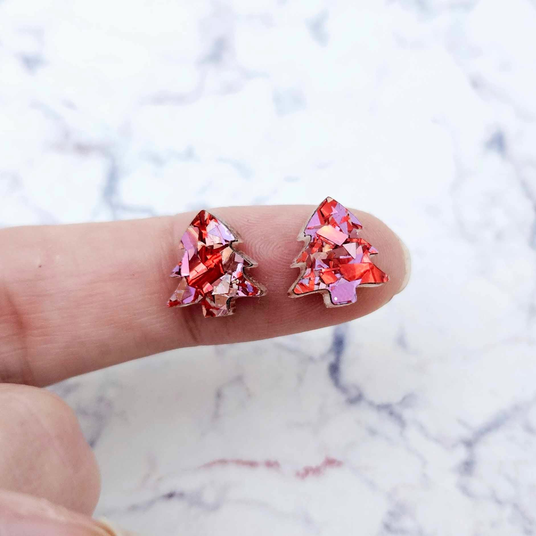 One pair of 12mm chunky love glitter acrylic Christmas tree stud earring blanks shown on a finger for size reference.