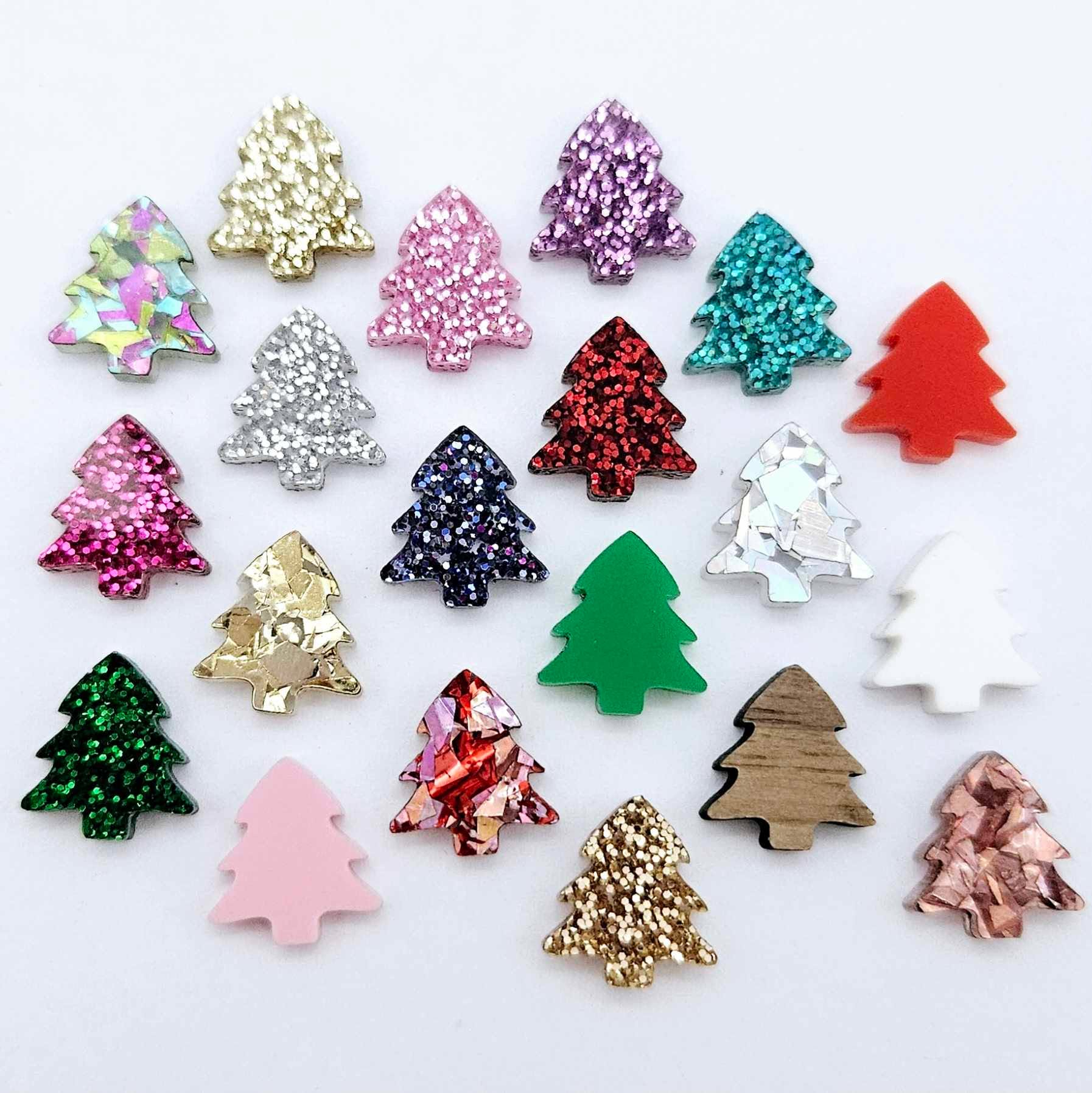 All 20 colours and finishes of 12mm mini Christmas tree stud earring blanks laying together, including glitter, solid acrylic and walnut veneer.