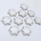 Five pairs of 16mm white marble acrylic snowflake stud earring blanks laying flat.