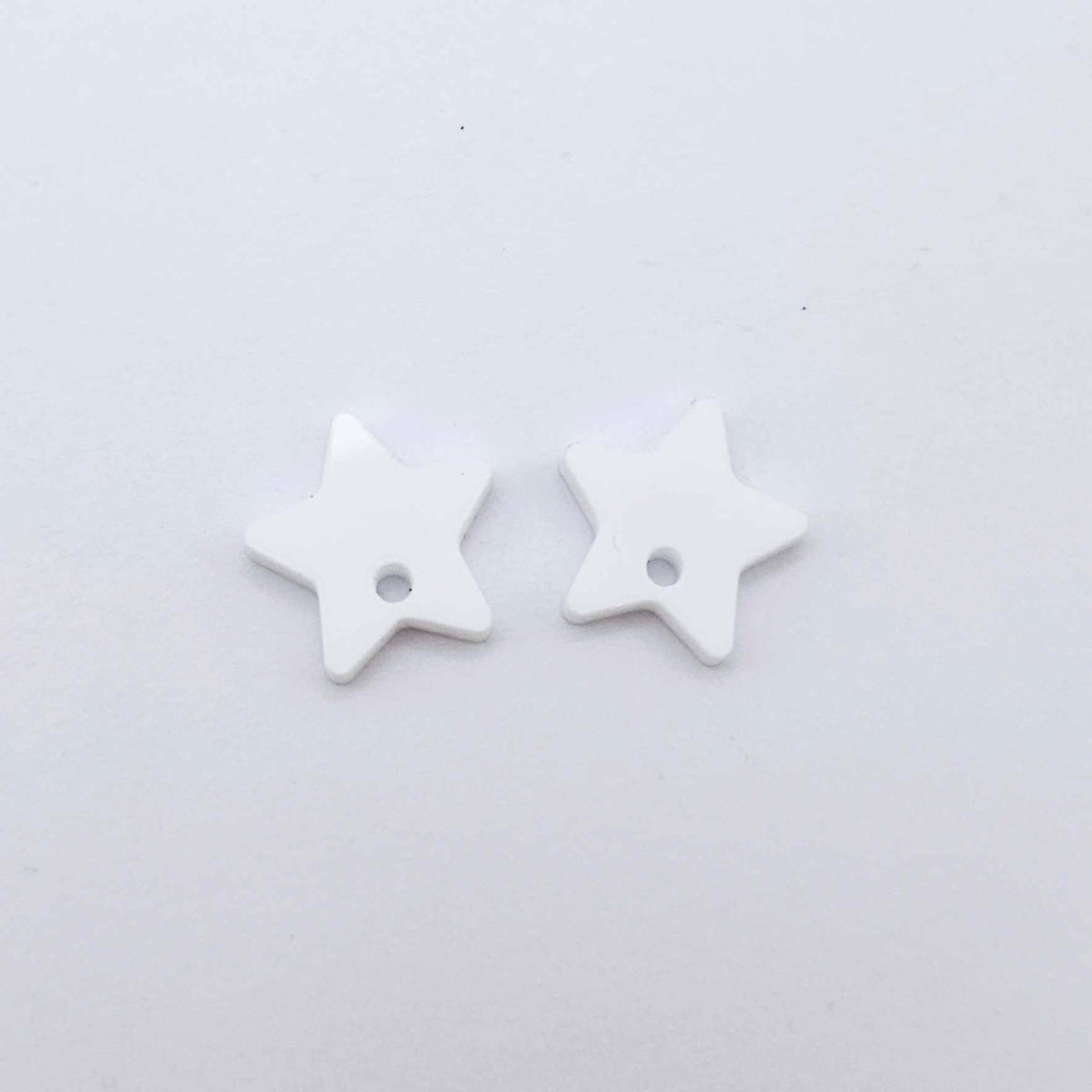 16mm white acrylic star earring toppers, one pair laid flat.