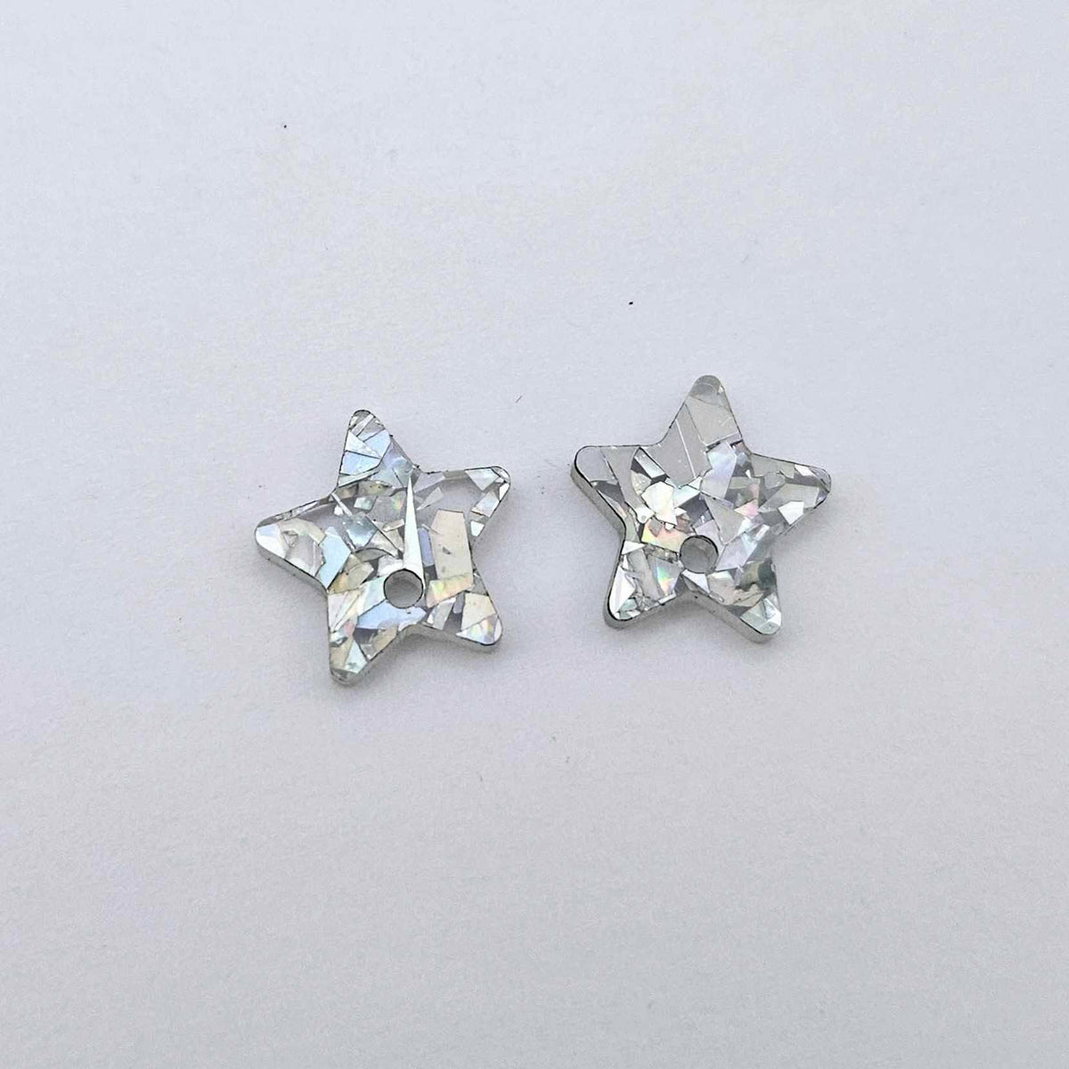 16mm holographic silver glitter acrylic star earring toppers, one pair laid flat.
