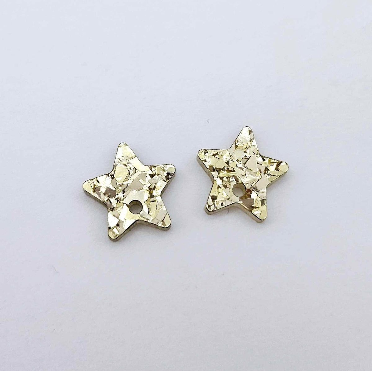 16mm chunky gold glitter acrylic star earring toppers, one pair laid flat.