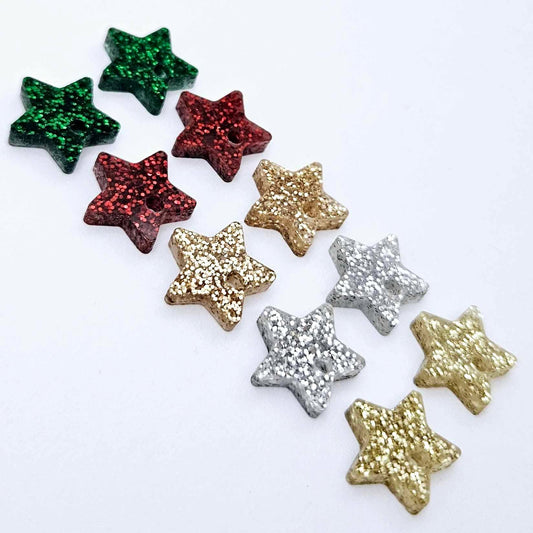 A selection of 14mm fine glitter acrylic star earring toppers in gold, silver, green, red and rose gold glitter laying flat