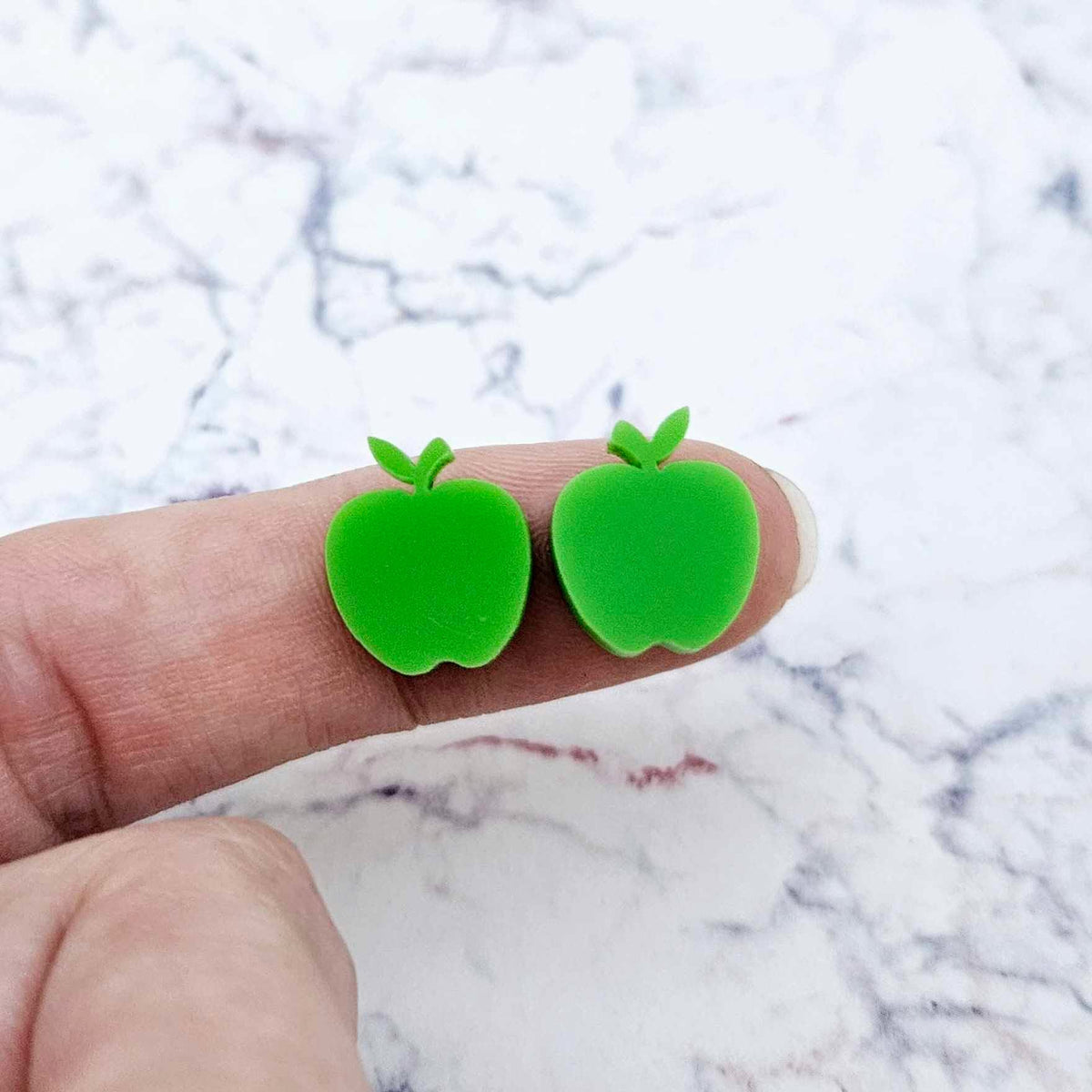 14mm solid lime green acrylic apple stud earring blanks shown on a finger for size reference.