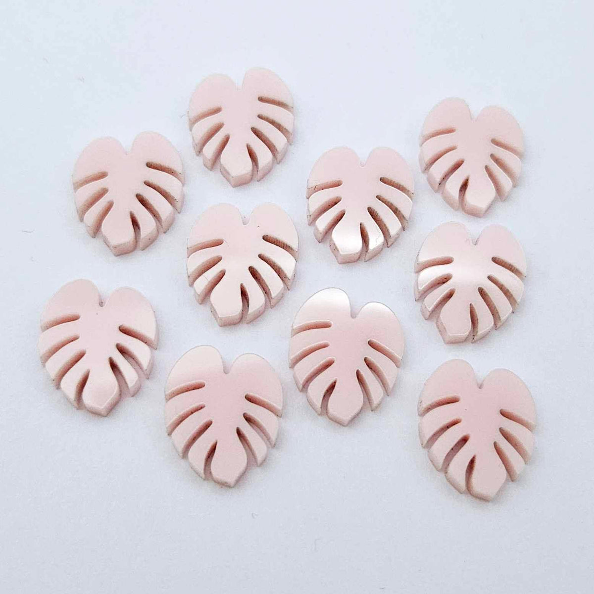 17mm strawberry milkshake pink monstera leaf acrylic stud earring blanks laid flat together.