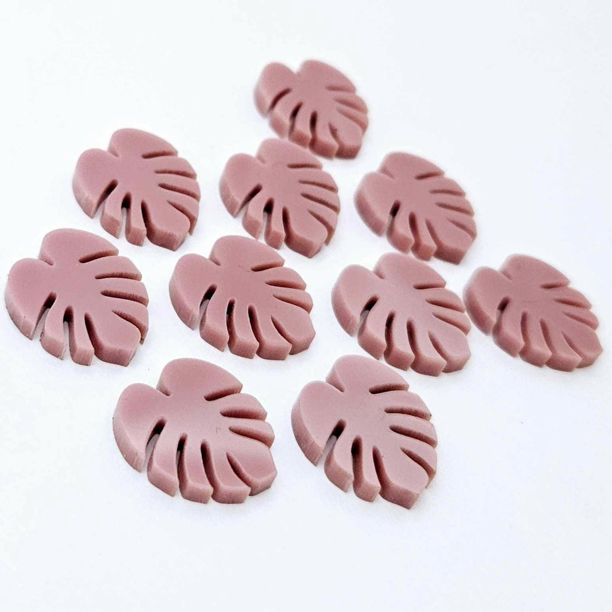17mm dusty rose pink acrylic monstera leaf acrylic stud earring blanks laid flat together.