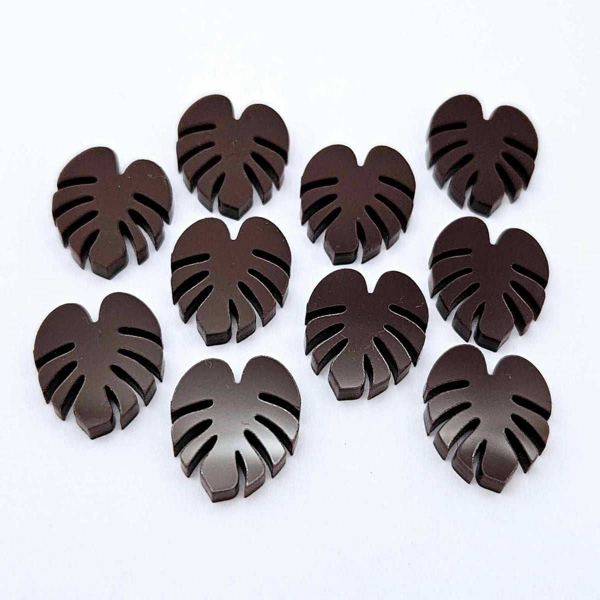 17mm chocolate brown acrylic monstera leaf stud earring blanks laid flat together.