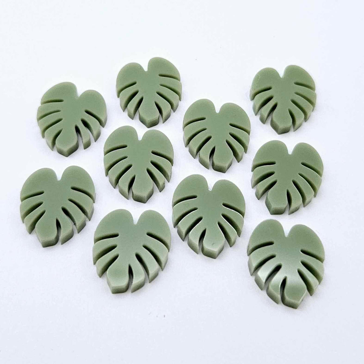 17mm olive green acrylic monstera leaf acrylic stud earring blanks laid flat together.