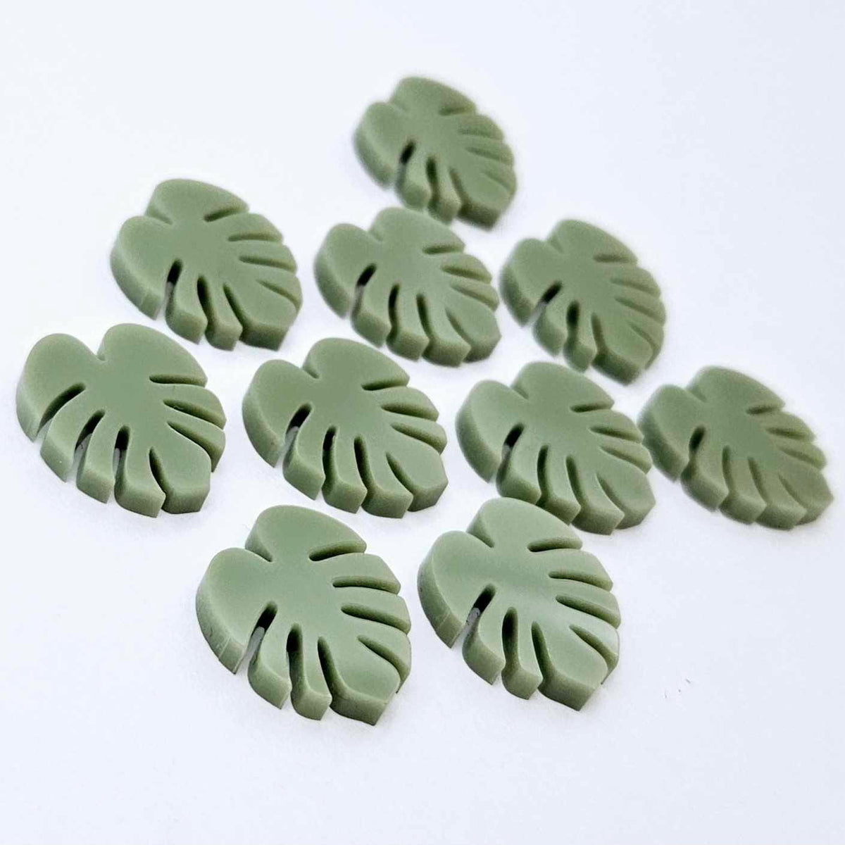 17mm olive green acrylic monstera leaf acrylic stud earring blanks laid flat together.