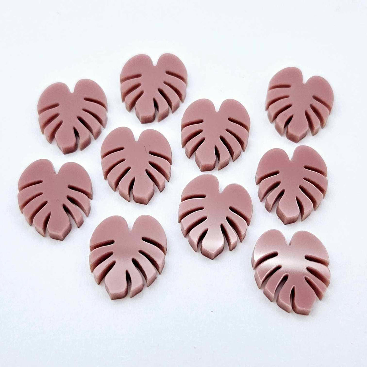 17mm dusty rose pink acrylic monstera leaf acrylic stud earring blanks laid flat together.