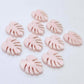 17mm strawberry milkshake pink monstera leaf acrylic stud earring blanks laid flat together.