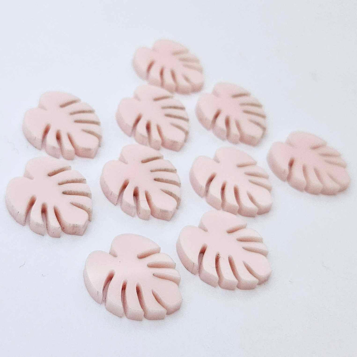 17mm strawberry milkshake pink monstera leaf acrylic stud earring blanks laid flat together.