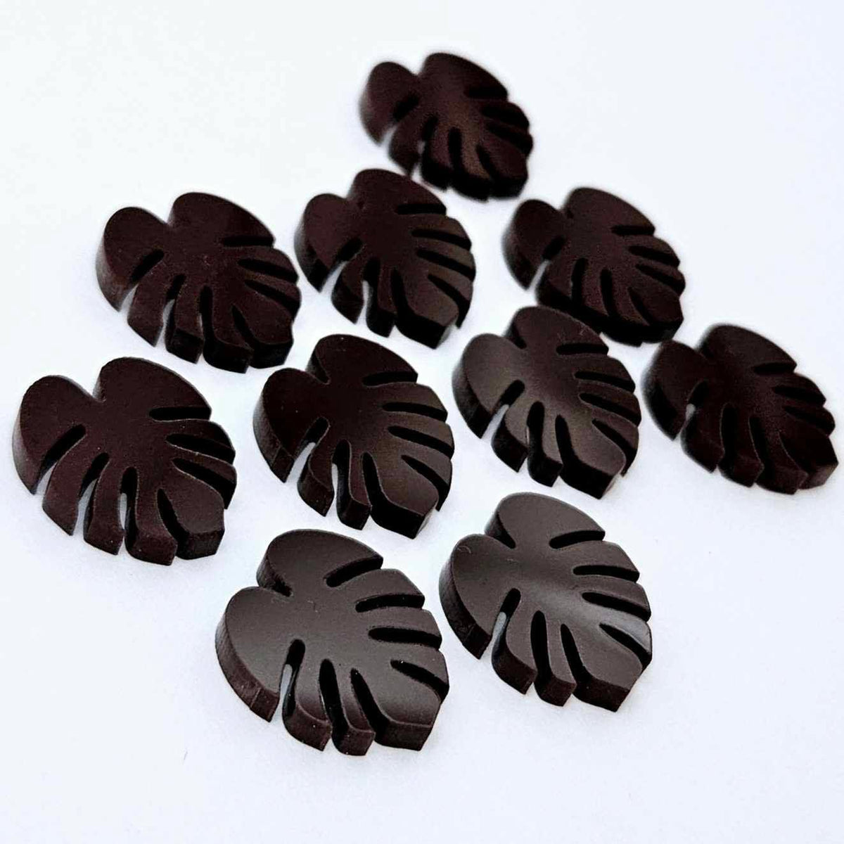 17mm chocolate brown acrylic monstera leaf stud earring blanks laid flat together.