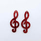One pair of 40mm red glitter acrylic treble clef earring dangle blanks laid flat.
