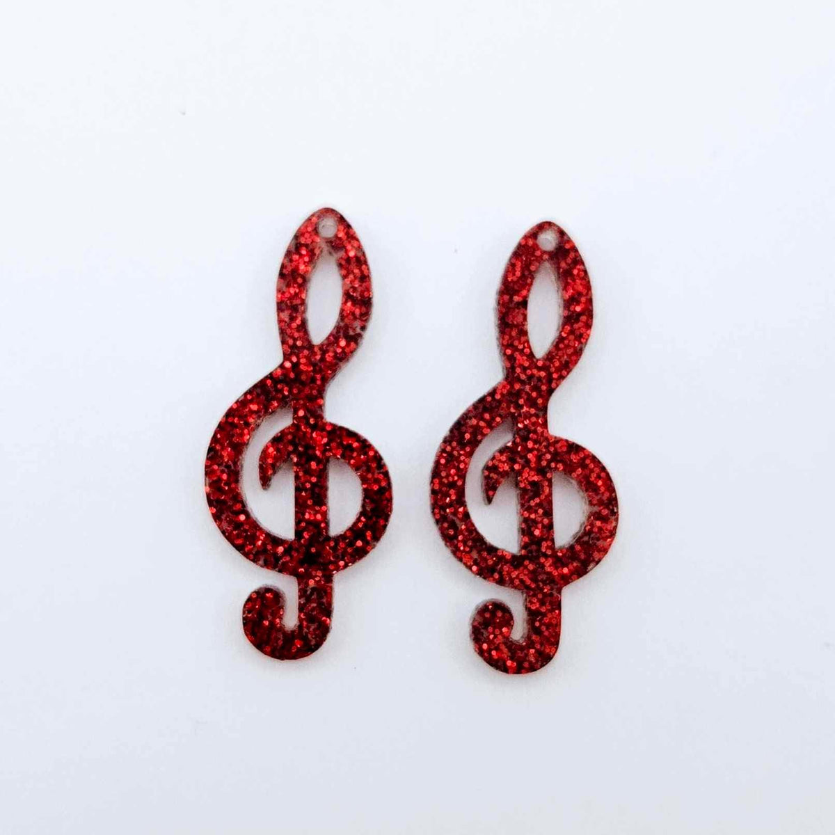 One pair of 40mm red glitter acrylic treble clef earring dangle blanks laid flat.