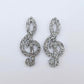 One pair of 40mm silver glitter acrylic treble clef earring dangle blanks laid flat.